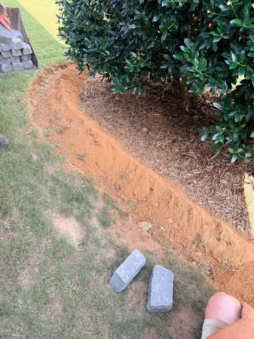 Installing shrubs around a stone border in a yard.